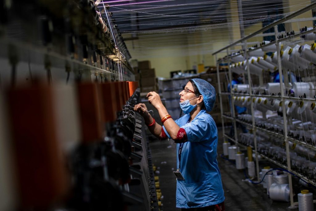 A textile worker is tending to machinery.